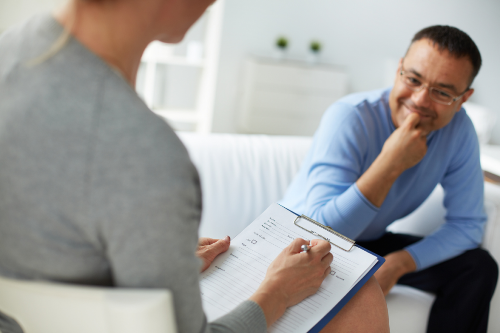 Poradce naslouchá zaměstnanci, což ilustruje důležitost osobní komunikace v rámci psychologie pracovní bezpečnosti na pracovišti.